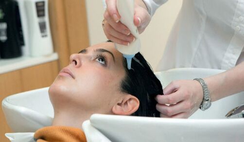 Der Meister trägt das Produkt auf, während er durch die Haare geht