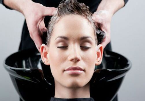 Einem Mädchen wird das Produkt aufgetragen, während es sich durch die Haare fährt